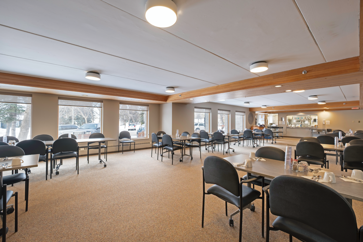 Large, light-colored room with rows of tables and chairs, suitable for a community or senior center dining area.